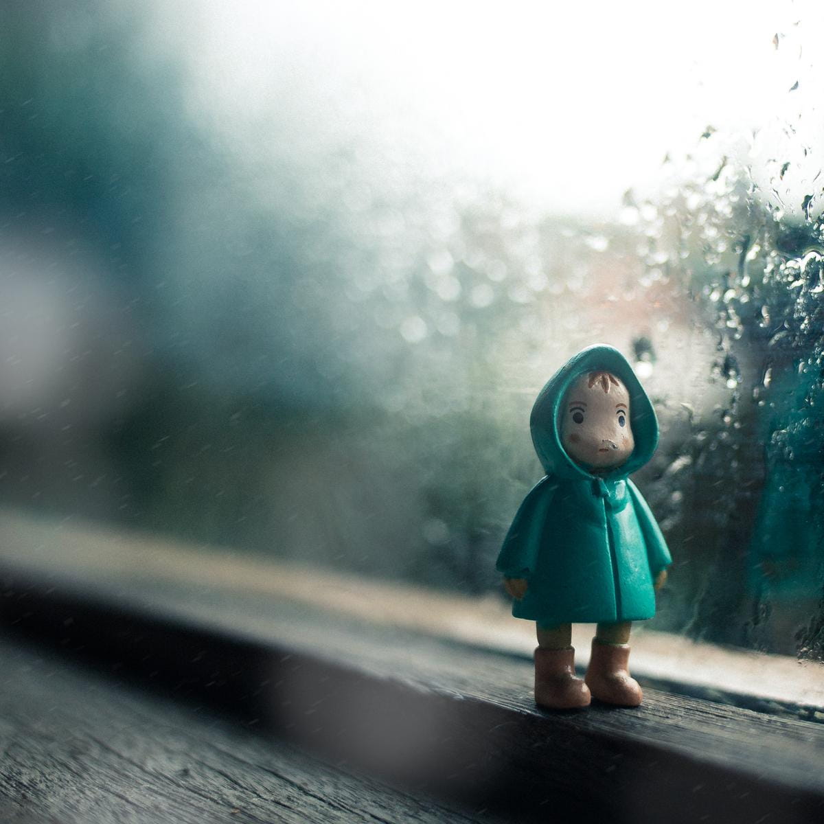 雨合羽を着た人形が窓辺で微笑む